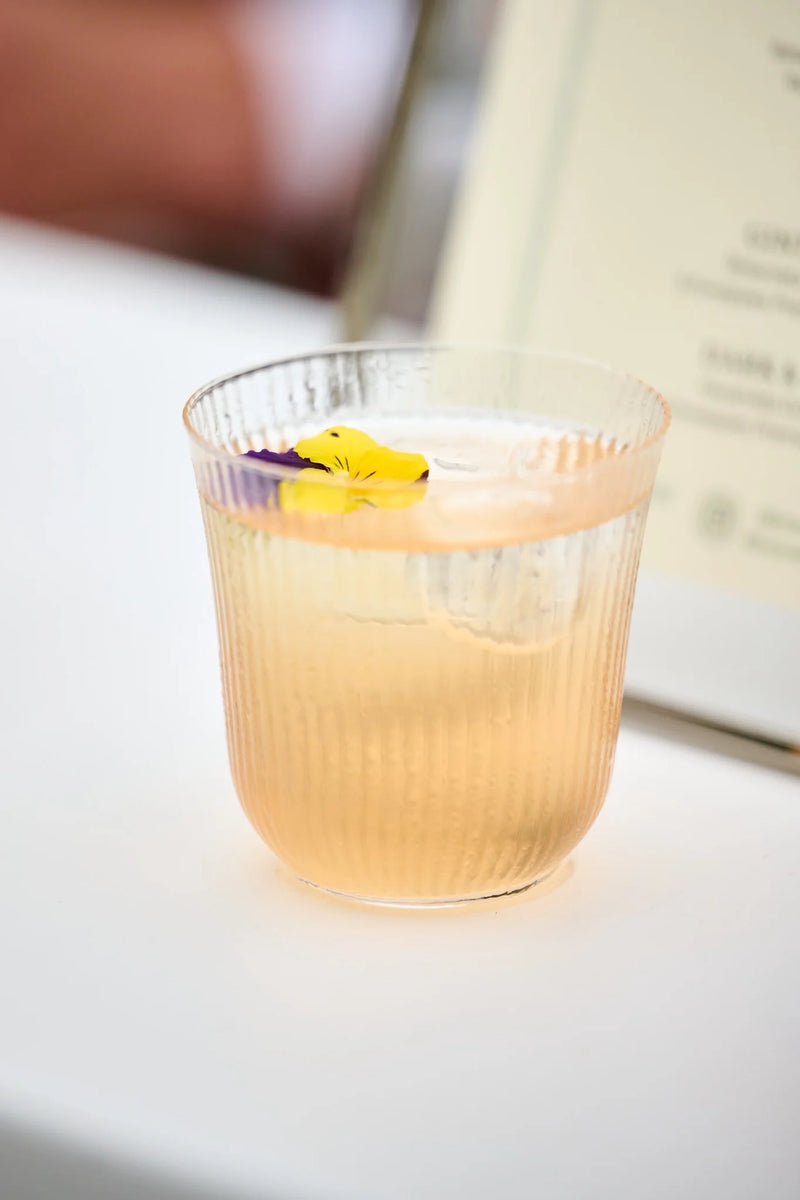 Enhance Your Mother's Day Mocktails with Edible Flower Garnishes in a beautifully presented drink.