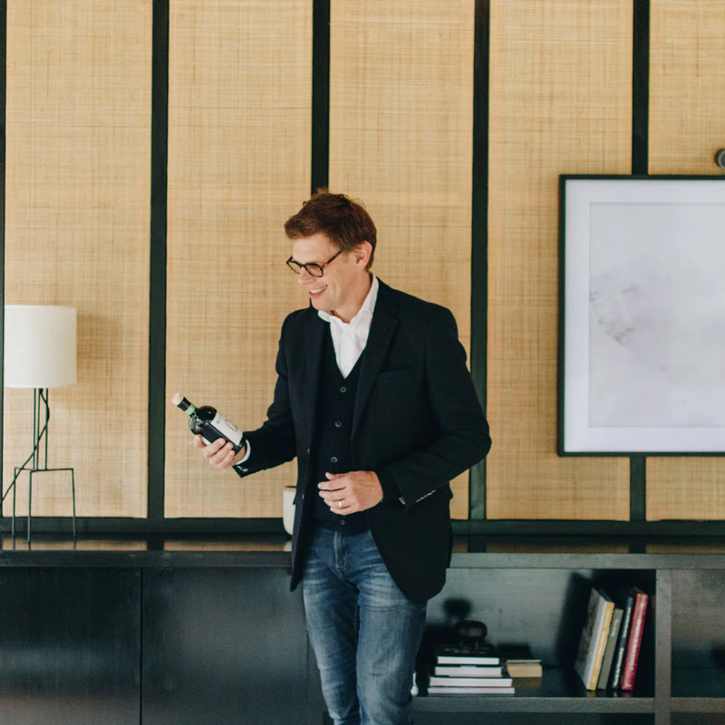 Niets supported by Finance&Invest.Brussels: a man holding a bottle in a stylish interior.