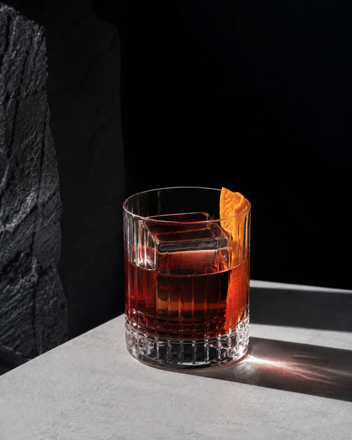 Negroniets cocktail served in a glass with ice and an orange peel garnish on a light surface.