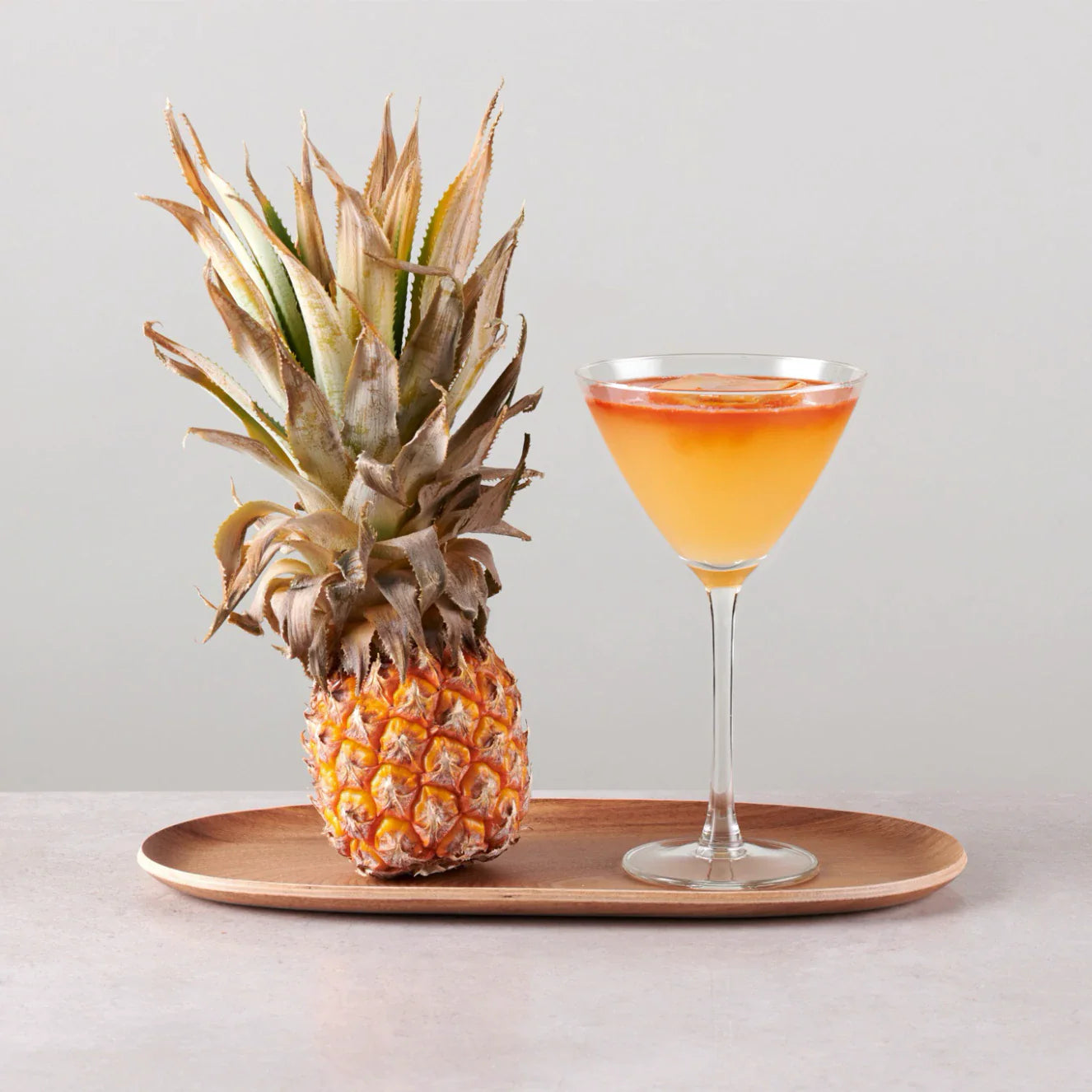 Harvard Pine & Apple cocktail served with a fresh pineapple on a wooden platter.