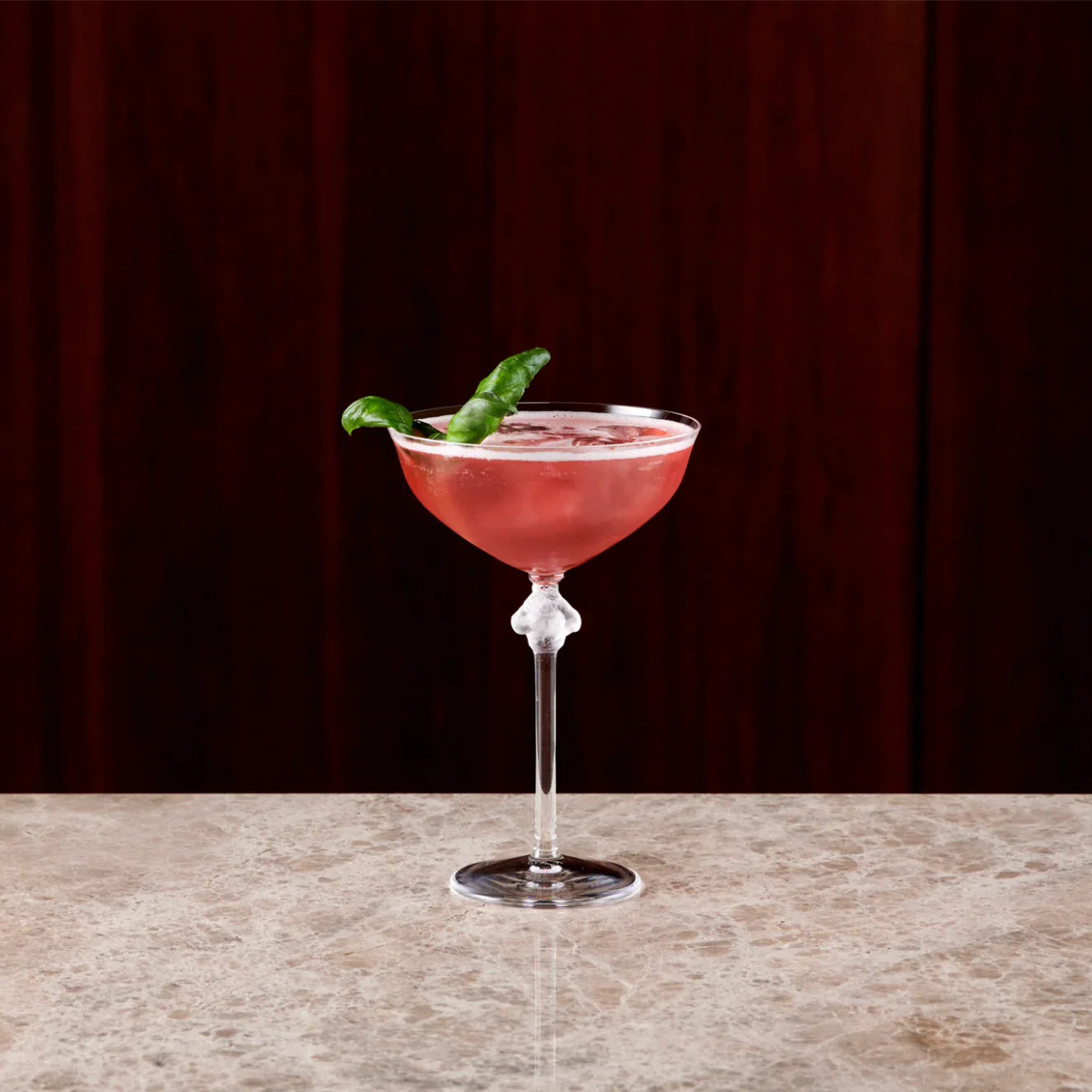 A beautifully garnished Parson's cocktail, featuring pomegranate and lemon, served in an elegant glass.