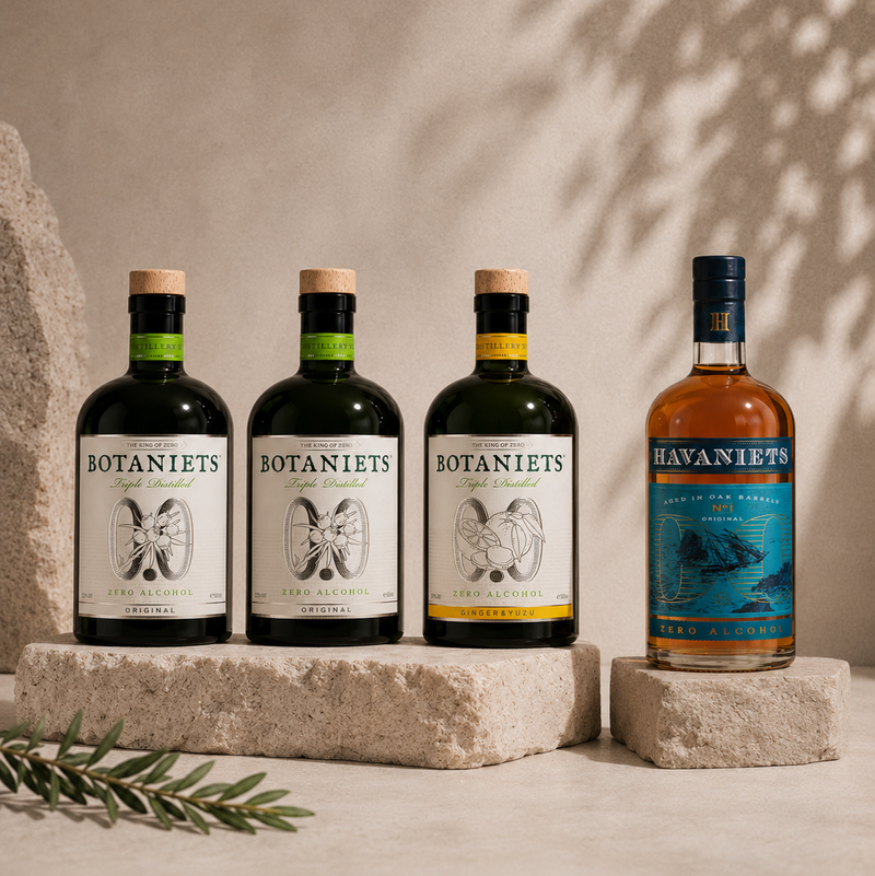 Four bottles of Botaniets and Havaniets coffee-infused alcoholic beverages arranged on stone blocks against a textured beige wall with leaf shadows.